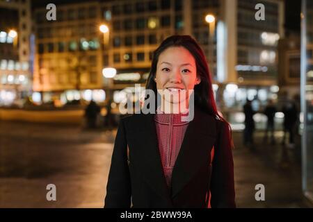 Porträt einer selbstbewussten jungen Frau in der Stadt bei Nacht, Frankfurt, Deutschland Stockfoto