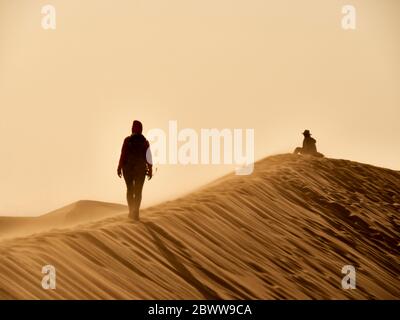 Frau, die auf dem Kamm einer Düne in der Wüste, Walvis Bay, Namibia, läuft Stockfoto