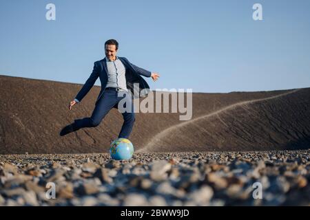 Reifer Geschäftsmann spielt Fußball mit einer Kugel auf einem stillgespielten Minentipp Stockfoto