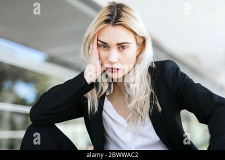 Porträt einer jungen Geschäftsfrau mit gefärbten blonden Haaren in schwarzem Anzug Stockfoto