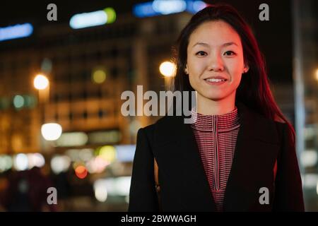 Porträt einer selbstbewussten jungen Frau in der Stadt bei Nacht, Frankfurt, Deutschland Stockfoto