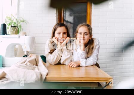 Portrait von zwei Mädchen lehnte sich auf Tisch mit Nähmaschine zu Hause Stockfoto