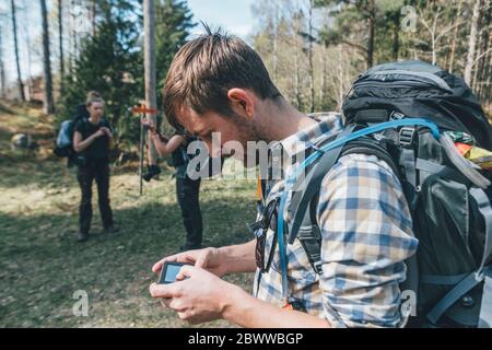 Junger Mann überprüft Navigationsgerät im Wald Stockfoto