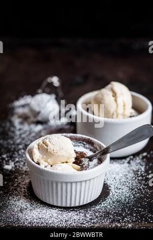 Studio Schuss von Tassen geschmolzener Schokoladenkuchen mit Vanilleeis und Puderzucker Stockfoto