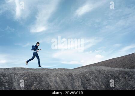 Reifer Geschäftsmann springt auf eine stillgediente Mine Spitze Stockfoto