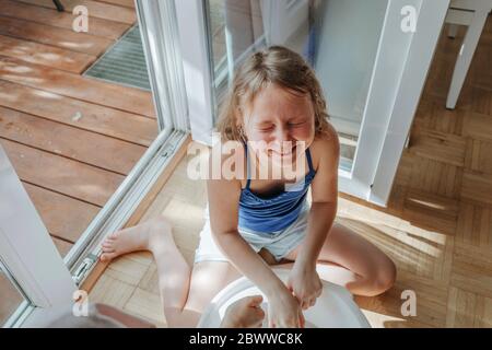 Portrait von lachenden Mädchen sitzt auf dem Boden zu Hause mit Eimer Stockfoto