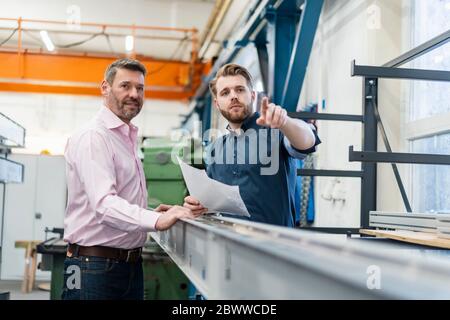 Zwei Männer, die in einer Fabrik ein Arbeitstreffen abhalten Stockfoto