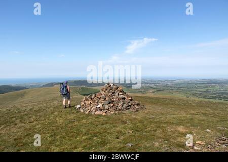 Walker Genießen Sie den Blick nach Westen vom Gipfel von Grike in Richtung der Küste an einem heißen Sommertag, Lake District, Cumbria, Großbritannien Stockfoto