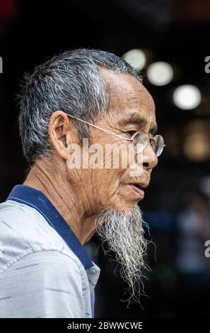 Feng Huang, China - August 2019 : Porträt eines alten chinesen mit grauem Bart und kleiner runder Brille Stockfoto