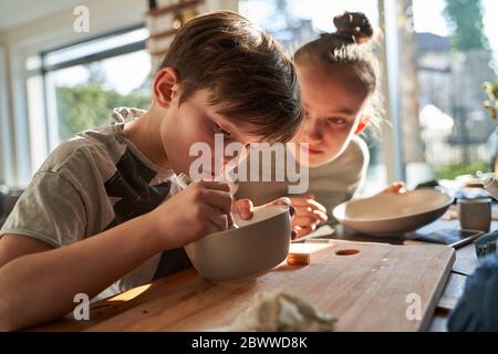 Bruder und Schwester zu Hause Malerei Geschirr mit Porzellanfarbe Stockfoto