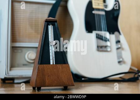 Metronom mit E-Gitarre und altem Radio im Hintergrund Stockfoto