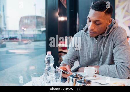 Junger Mann mit Smartphone in einem Café Stockfoto