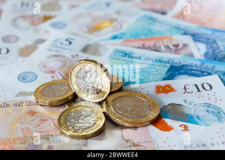 Ein Stapel von einem Pfund £ Münzen britischen Geld Sterling auf neue Polymer £10 und £5 Noten GBP Nahaufnahme. England Großbritannien