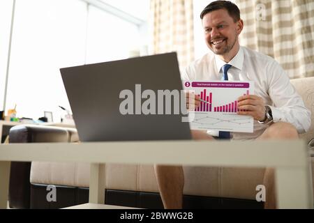 Guy sitzt zu Hause vor Laptop mit Bericht Stockfoto