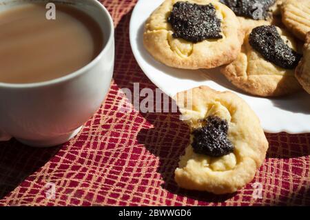 Gebissene Plätzchen mit Mohnfüllung und Kaffee bei Tageslicht, Background, Food-Fotografie Stockfoto