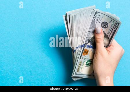 Blick von oben auf die weibliche Hand mit einem Pack von hundert Dollar Scheine auf farbigen Hintergrund. Lohn und Gehalt Konzept mit leeren Raum für Ihr Design. Stockfoto