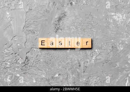 Osterwort auf Holzblock geschrieben. Ostertext auf Zementtisch für Ihren Entwurf, Konzept. Stockfoto