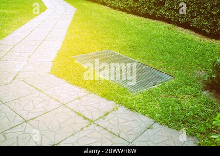 Pfad und Drainage im Garten mit Lichtauchen. Stockfoto