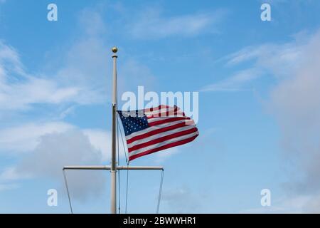 Amerikanische Flagge auf Mast im steifen Wind vor blauem Himmel, horizontaler Aspekt Stockfoto