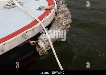 Gewebte und gewickelte Seil Boot Stoßstange auf einem Segelboot im Wasser, maritime Details, horizontale Aspekt Stockfoto