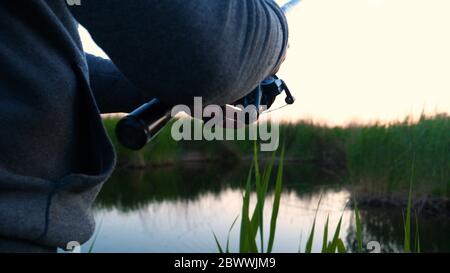 Ein Mann in der Natur der Fischerei ruht, wirft den Köder in den Fluss, dreht die Spule und heben Sie den Köder an die Spitze. Konzept: Angeln, Urlaub Stockfoto