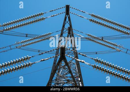 Nahaufnahme von Details von Abschnitten eines Hochspannungsmasten vor einem lebendigen blauen Himmel Stockfoto