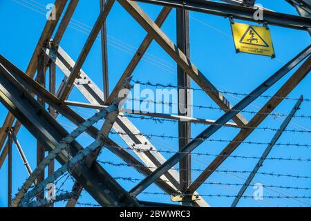 Detail Warnschild auf einem Strommast gegen einen blauen Himmel Stockfoto