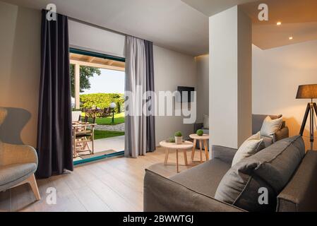 Modernes grau-Holz-Wohnzimmer mit großem französischen Fenster und grüner Gartenterrasse. Umweltfreundliches Innenkonzept Stockfoto