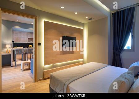 Modernes graues, blaues, hölzernes Schlafzimmer in einem kleinen Studio-Apartment. Modernes, minimalistisches Interieur des Hotel-Flat-Zimmers mit Kopierbereich und tv-Panel Stockfoto