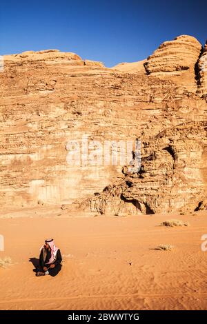 Ein Beduinen-Mann sitzt vor dem Hintergrund der jordanischen Wüste Wadi Rum oder Tal des Mondes Stockfoto