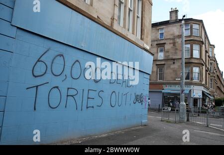 Eine Person passiert Graffiti im Zusammenhang mit dem Coronavirus in Glasgow, während Schottland in Phase eins des Plans der schottischen Regierung geht, die Sperre schrittweise zu heben. Stockfoto