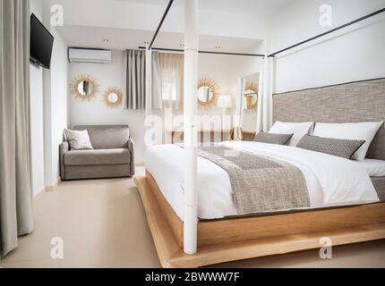 Leere helle Einrichtung eines modernen Öko-Stil Schlafzimmer mit Holzmöbeln, grauem Baumwolltextil, weißen Wänden, beigefarbenen Keramikfliesen Boden Stockfoto