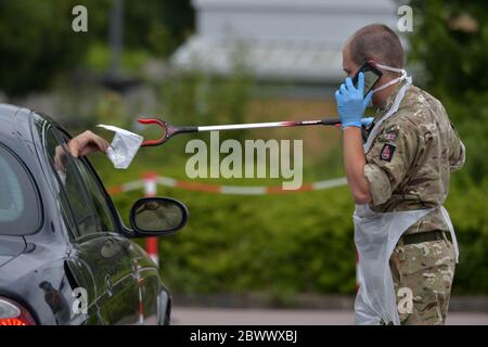 Eine Person übergibt ein fertiger Coronavirus-Selbsttest-Paket durch ein Autofenster an einen Reservisten des Royal Anglian Regiment im Harlow Football Club, Harlow, nachdem Maßnahmen eingeführt wurden, um England aus der Sperre zu holen. Stockfoto