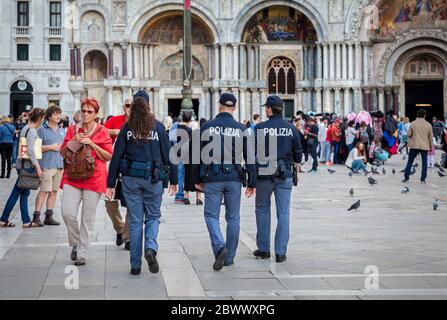 Eine weibliche und zwei männliche italienische Polizeibeamte patrouillieren unter Touristen auf dem Markusplatz in Venedig Stockfoto