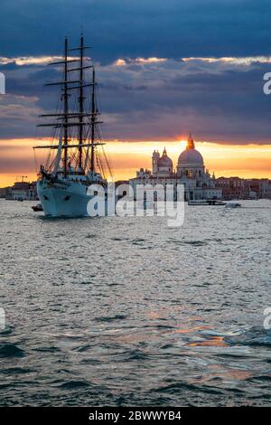 Segelschiff mit drei Masten, MV Sea Cloud ll, verlässt Venedig, Italien, unter einem warmen Sonnenuntergang, mit der Basilika Santa Maria della Salute im Hintergrund Stockfoto