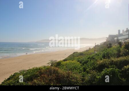 Grüner Hügel mit touristischen Unterkünften und dem Strand von Wilderness. Blick auf den wilden Indischen Ozean. Auf Der Garden Route, Südafrika, Afrika. Stockfoto