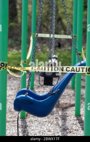 Swing mit Vorsicht Klebeband verwendet, um Parks während der Pandemie zu schließen. Spielgeräte aus nächster Nähe. Vorsichtsmaßnahmen für die Eindämmung des Coronavirus. Öffentliche leeren Stockfoto