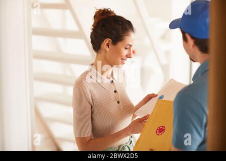 Junge Frau zufrieden die Lieferung sie Pakete von Postbote Stockfoto