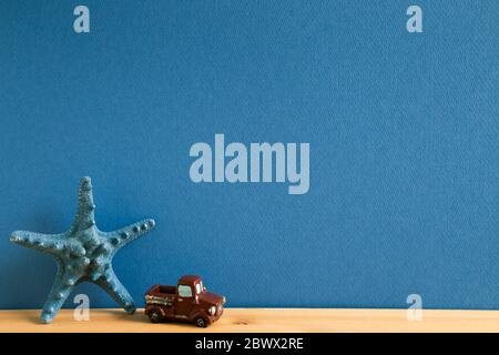 Blue starfish and mini car on wooden table with blue background, Summer vacation concept Stockfoto