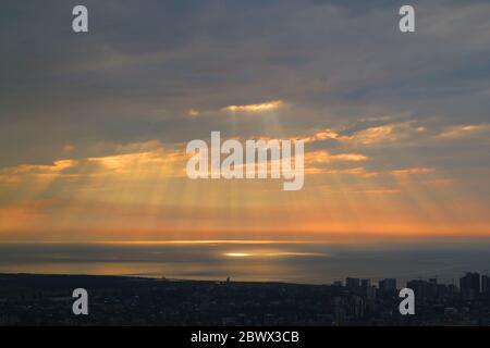Atemberaubender Sonnenaufgang mit der Engelsleiter über dem Meer und der Stadt Stockfoto