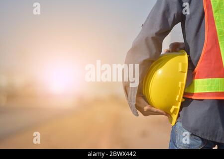 Nahaufnahme Engineering Holding Yellow Helm Hard Hut Sicherheit und Straßenbau Hintergrund Stockfoto