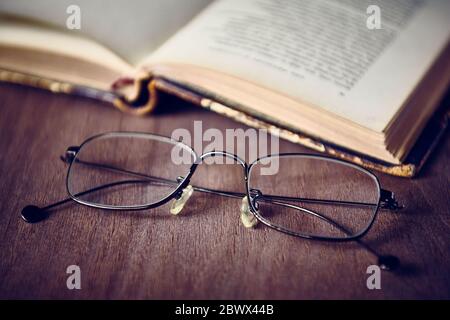 Brille und offenes altes Buch, Jahrgang, flacher DOF Stockfoto