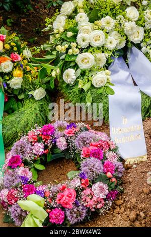 Nordrhein-Westfalen, Deutschland - Trauerkranz mit Bändern auf einem frischen Grab. Nordrhein-Westfalen, Deutschland - Trauerkraenze mit Trauerschleifen auf Stockfoto