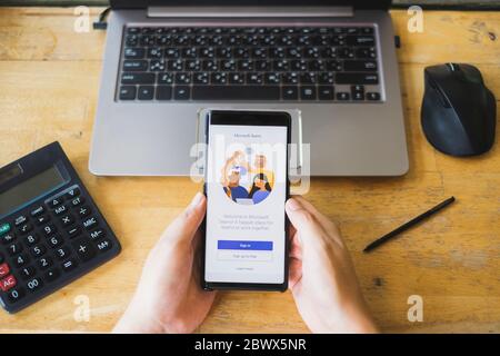 RAYONG, THAILAND - 9. MAI 2020 : Nahaufnahme der Microsoft Teams Business-Anwendung auf dem Smartphone-Bildschirm vor dem Tablet auf dem Holztisch. Anw Stockfoto