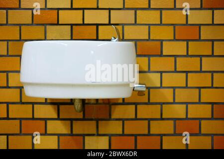 Altes weißes Keramikwaschbecken an der Ziegelwand. Stockfoto