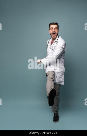 Ein Porträt eines Arztes, der vor grauem Hintergrund posiert Stockfoto