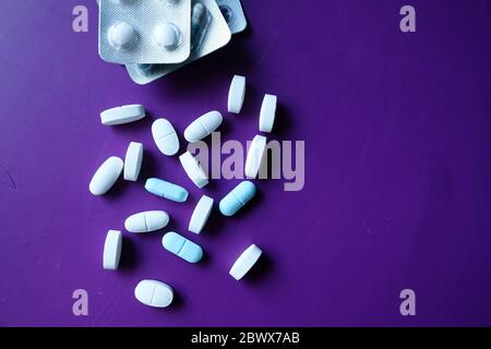 Draufsicht der weißen Pillen und Blister Pack auf lila Hintergrund Stockfoto