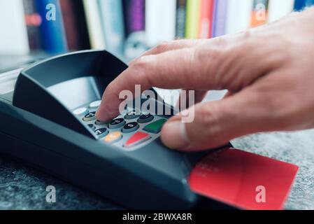 Nahaufnahme der Person, die die PIN-Nummer am POS-Zahlungsterminal für Kreditkarten eingibt Stockfoto