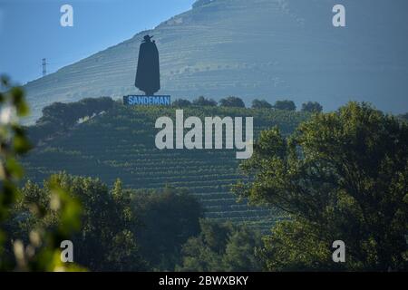 Die Weinberge des Douro Valley und der ironisch gekleidete Mann namens Don, der auf einem Hügel auf einem portugiesischen Studentencape mit Blick auf den Fluss in der Nähe von Régua N Portugal gekleidet ist Stockfoto