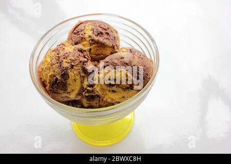 Kugeln Orange und Schokolade Eis in einem Glas Dessert Schüssel auf weißem Hintergrund mit Kopierraum. Selektiver Fokus Stockfoto